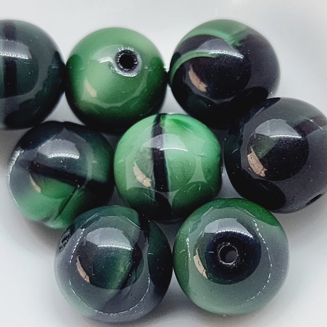 A collection of round opaque green and black beads with a glossy finish.