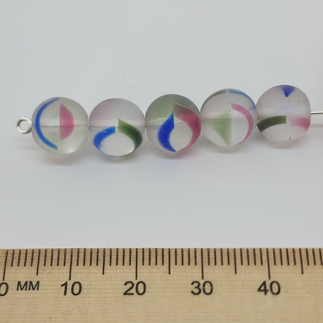 givre pressed glass beads on a pin with a ruler for scale on a white background
