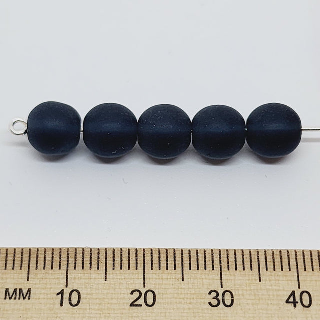 deep deep blue frosted beads on a pin with a ruler for scale on a white background
