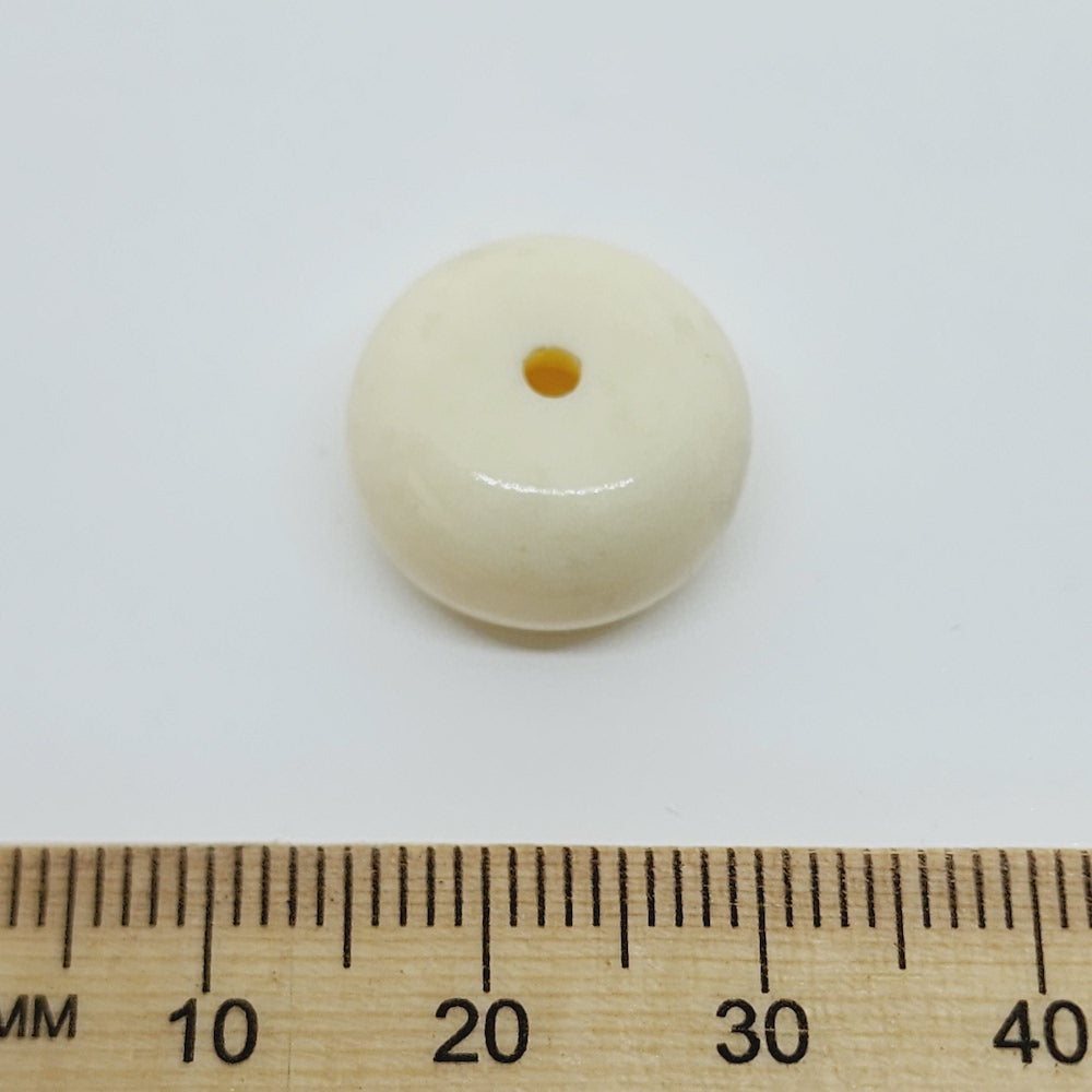 close up stone look beads with large threading hole and a glossy surface with a ruler for scale