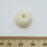 close up stone look beads with large threading hole and a glossy surface with a ruler for scale