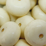 A collection of round, ivory-colored beads with a hole for stringing.