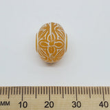 A collection of vintage orange and white baroque-patterned lucite beads with a white line bordering each bead against a ruler to show scale