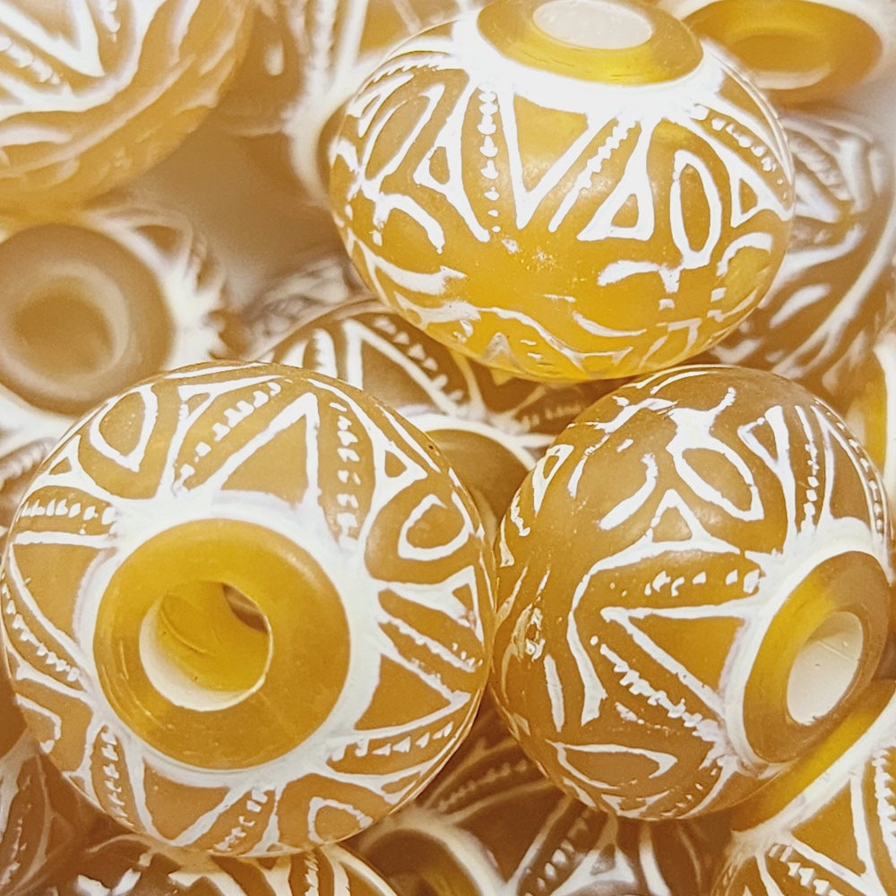 A collection of vintage orange and white baroque-patterned lucite beads with a white line bordering each bead 