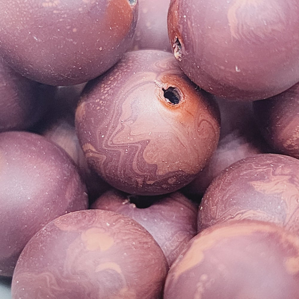 Close-up of marble finish wood look beads with a central hole.