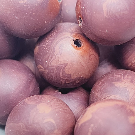 Close-up of marble finish wood look beads with a central hole.