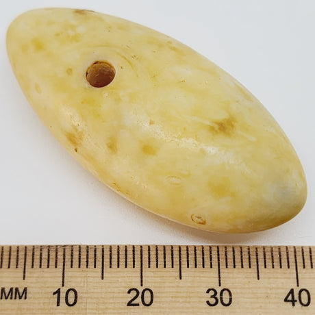 oval drop shape stone look pendant shape bead with a ruler for scale showing a hole at one end for threading