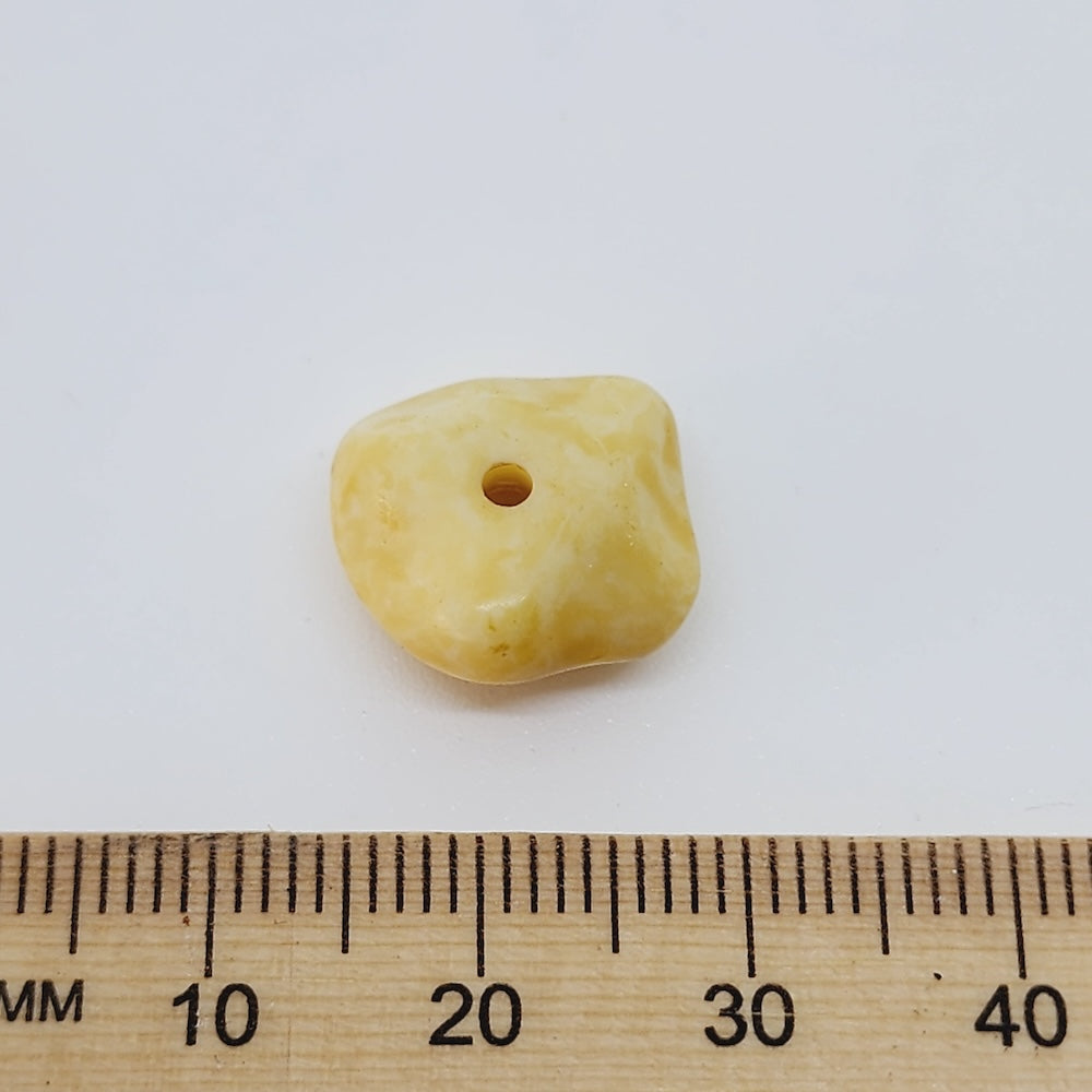 close up of one nugget bead that looks like stone with a ruler to show scale