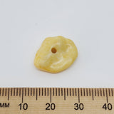 close up of one yellow stone look bead with a ruler to show scale