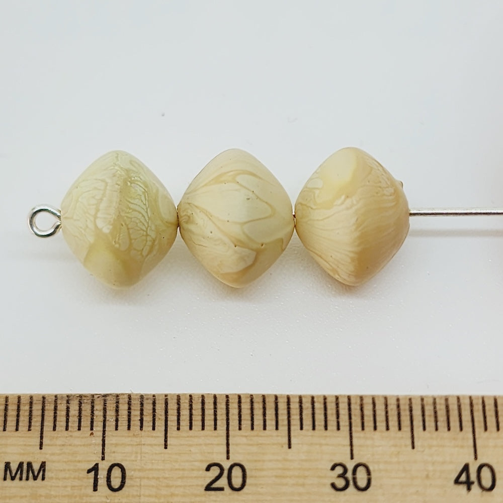 ufo shape wood look marbled beads in cream on a white surface with a ruler to show size