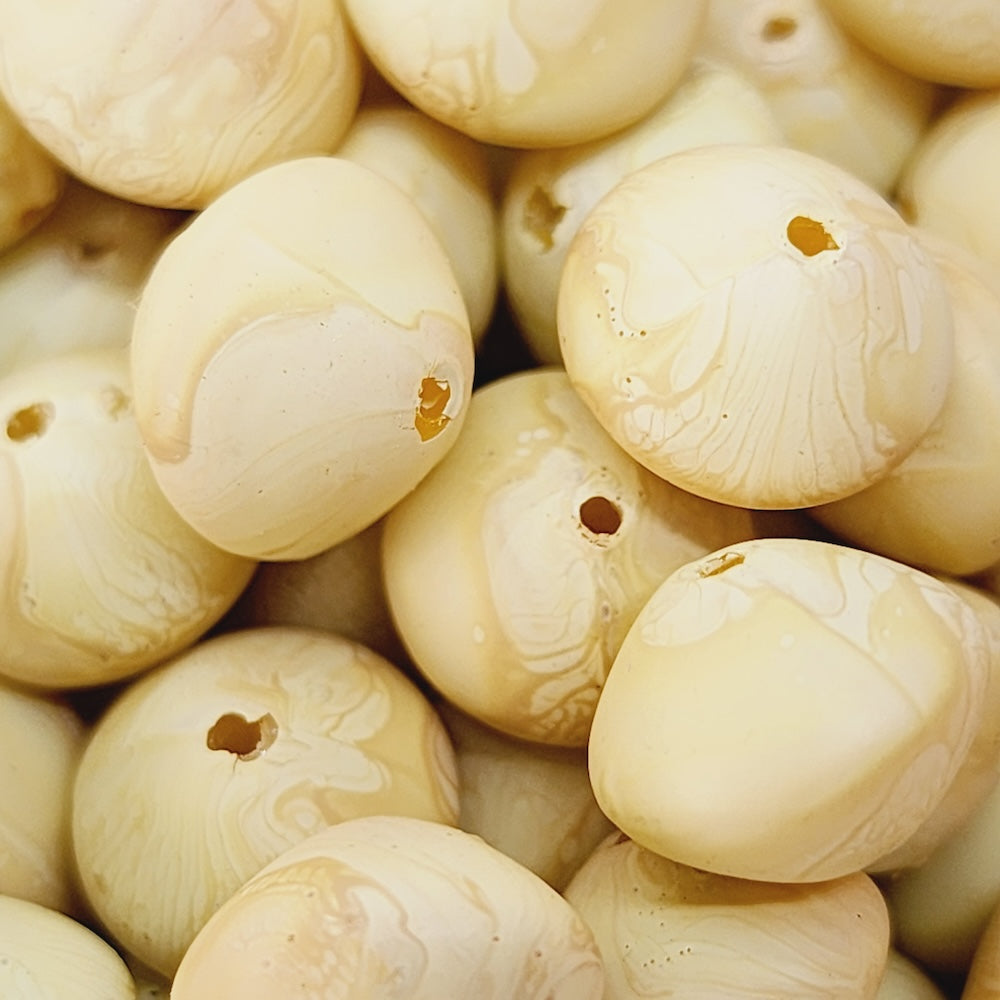 Close-up of marble finish wood look beads with a central hole.