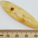 Cream spear shape bead with a large hole on a white background, next to a wooden ruler for scale.