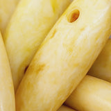 Close-up of ivory look stone lok freeform spear shape beads with a top drilled hole.