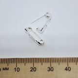 Silver brooch pin on a white background with a wooden ruler for scale.