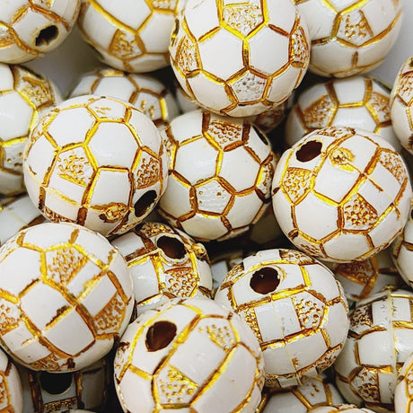 A collection of white beads with gold geometric patterns, resembling a soccer ball's texture, with holes for threading.