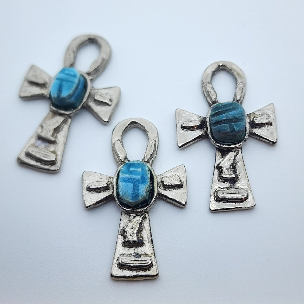 Three Metal Ankh vintage charms with turquoise blue tiny scarab beetle in the centre on a white background