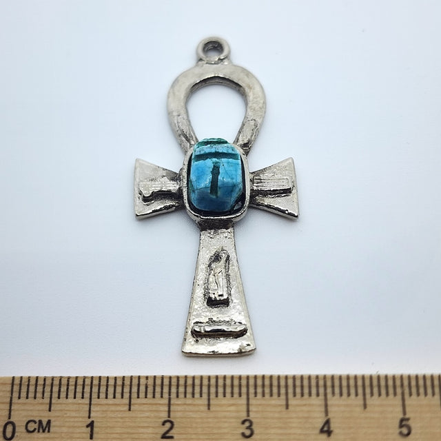 A vintage Egyptian ankh-shaped pendant charm with a scarab feature, handcrafted from faience, displayed against a white background with a measuring ruler at the bottom.