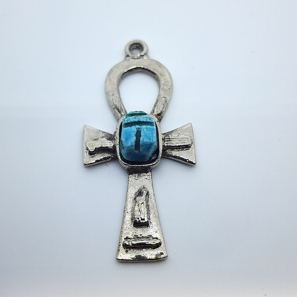 Metal Ankh vintage charm with turquoise blue tiny scarab beetle in the centre on a white background