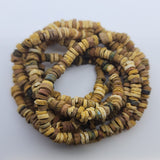 A strand of vintage faience clay beads with varying shades of beige, brown, and blue, knotted and strung together.