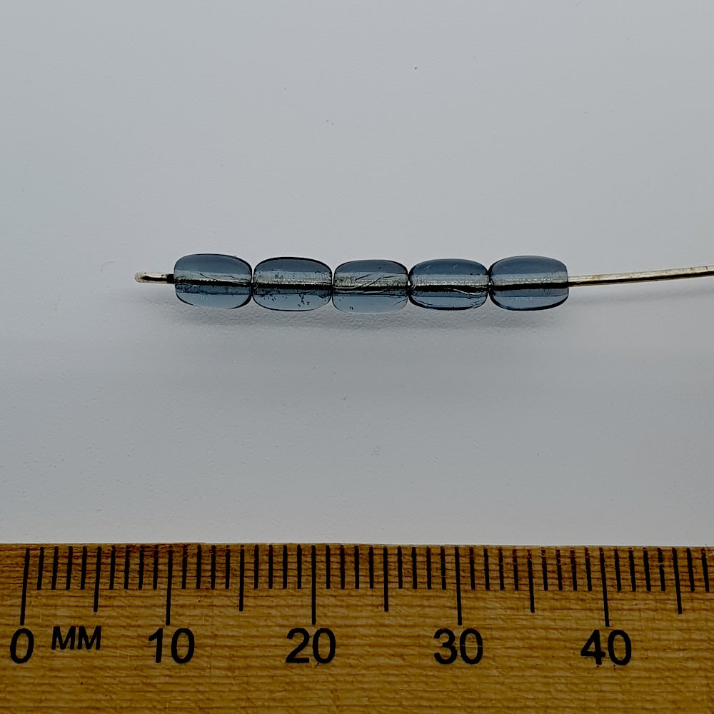 Set of blue beads on a stick with a wooden ruler for scale on a white background