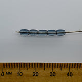 Set of blue beads on a stick with a wooden ruler for scale on a white background