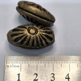 Two bronze-colored metal clay beads with intricate designs on a white background, accompanied by a ruler for scale.