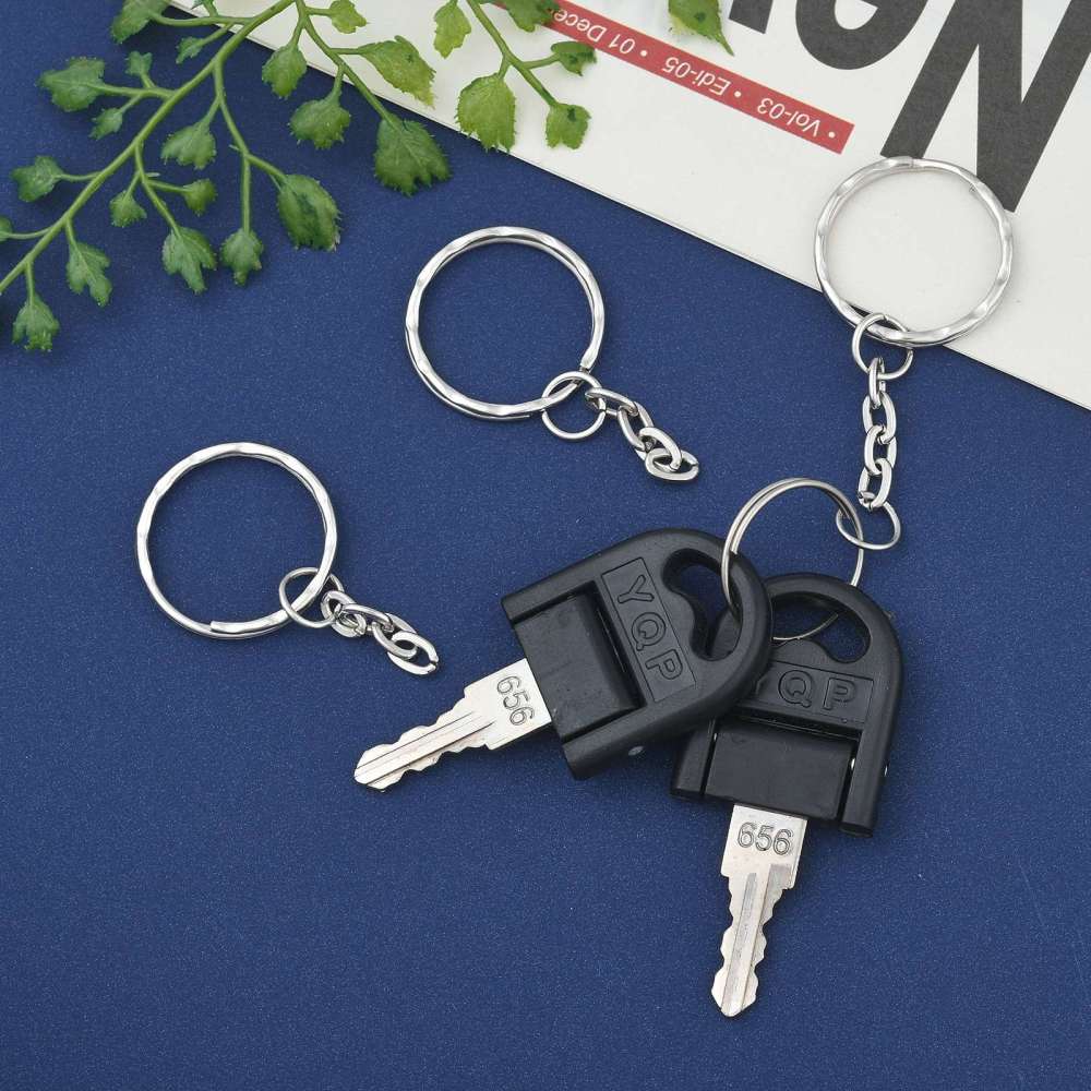 Keychain with keys on a blue surface with green leaves and a magazine in the background