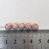Marbled pink and white beads on a ruler for size reference