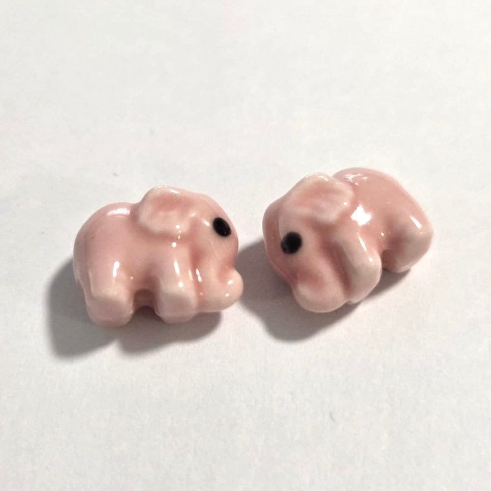 pink elephant beads facing each other on a white surface