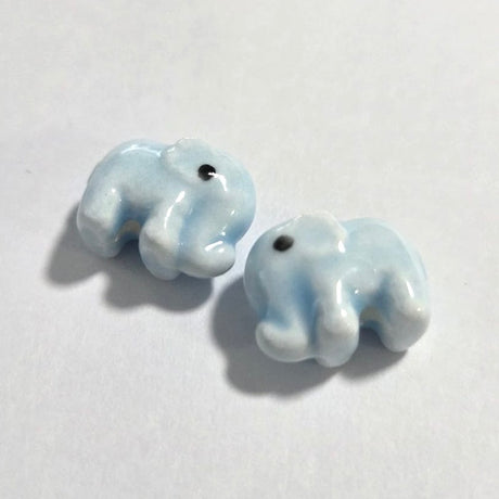 Two small ceramic elephant figurines on a white background
