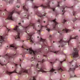 A collection of transparent pink glass beads with yellow red and white eyes, used for making jewelry.