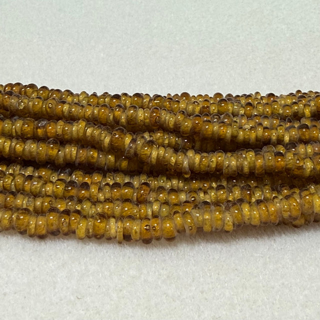 amber brown donut shaped Indonesian glass bead strands on a white background