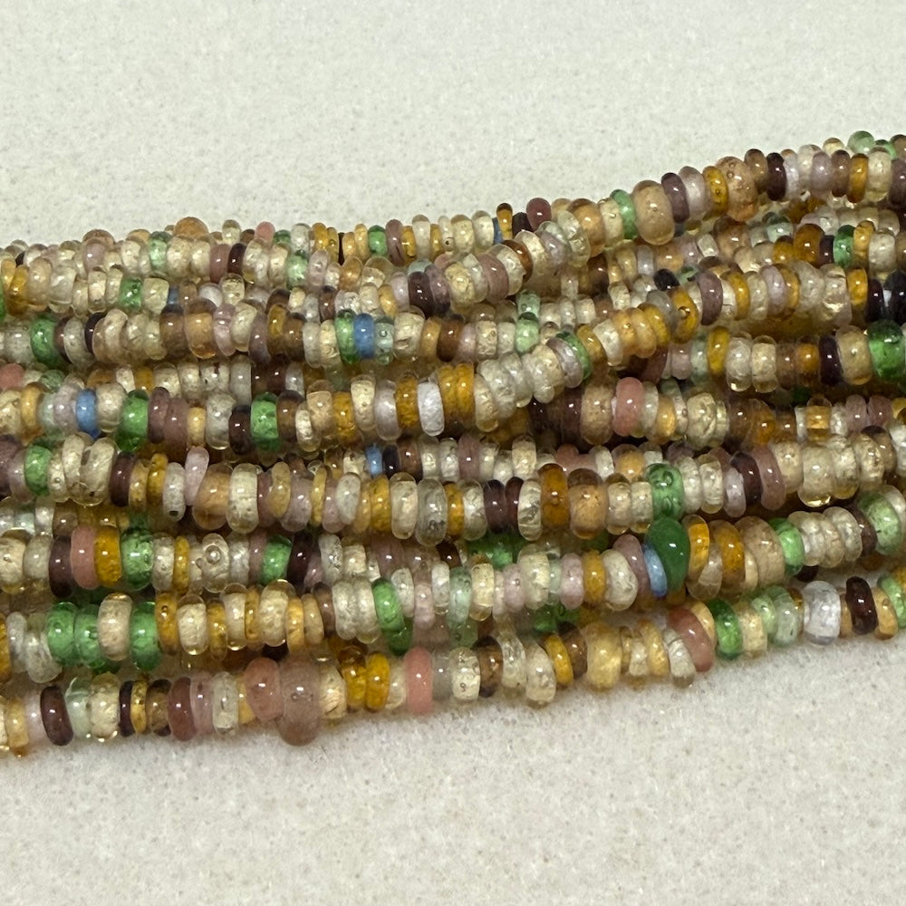 Multicolored donut shaped Indonesian glass bead strands on a white background
