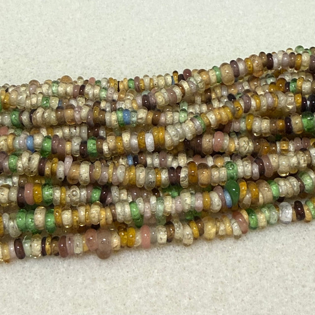 Multicolored donut shaped Indonesian glass bead strands on a white background