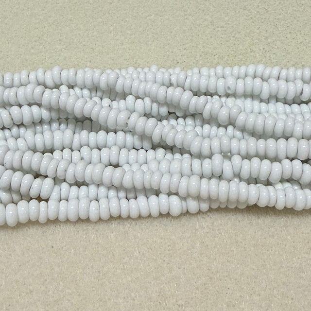opaque white donut shaped Indonesian glass bead strands on a white background