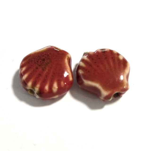Two ceramic beads shaped like shells on a white background
