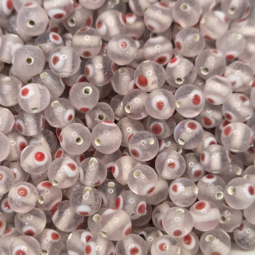A collection of transparent clear glass beads with red and white eyes, used for making jewelry.