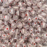 A collection of transparent clear glass beads with red and white eyes, used for making jewelry.