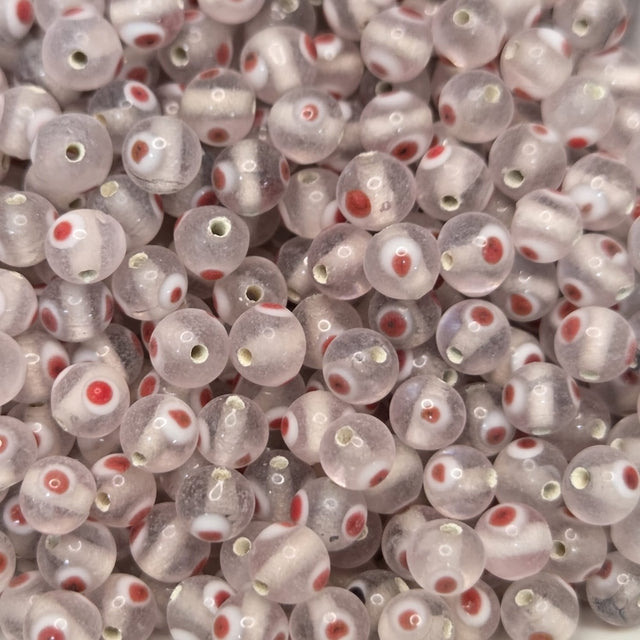 A collection of transparent clear glass beads with red and white eyes, used for making jewelry.