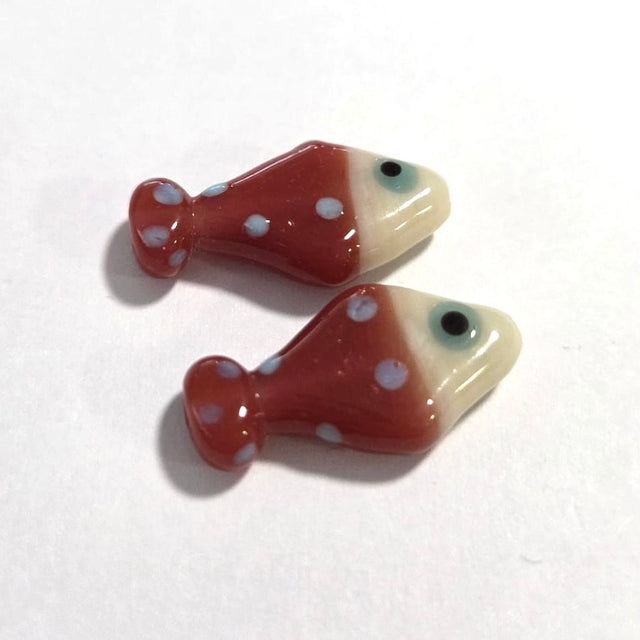 Two ceramic fish-shaped beads with white polka dots on a white background