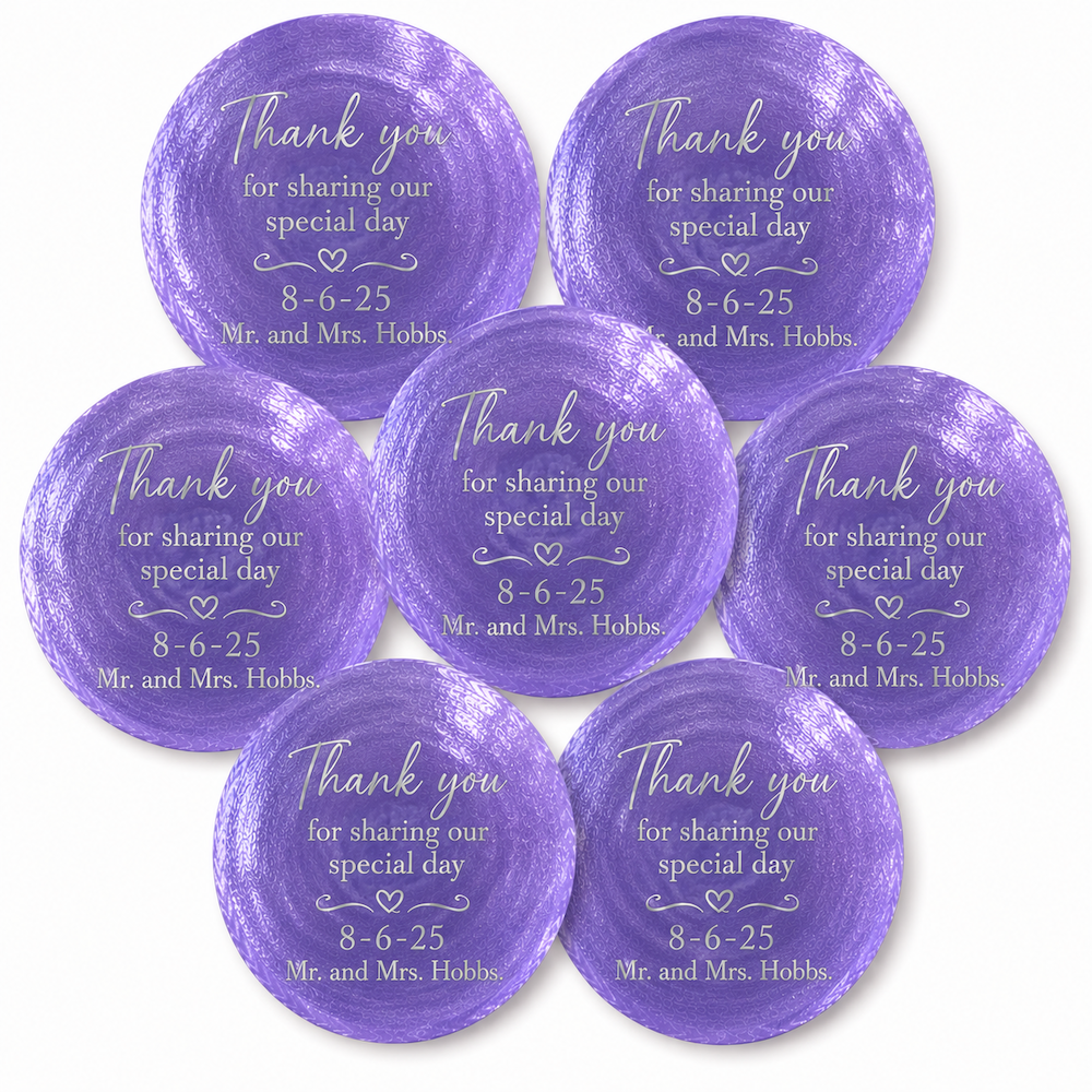 Seven round purple watercolor-style shell party favors or place settings with white printed text reading 'Thank you for sharing our special day 8-6-25 Mr. and Mrs.