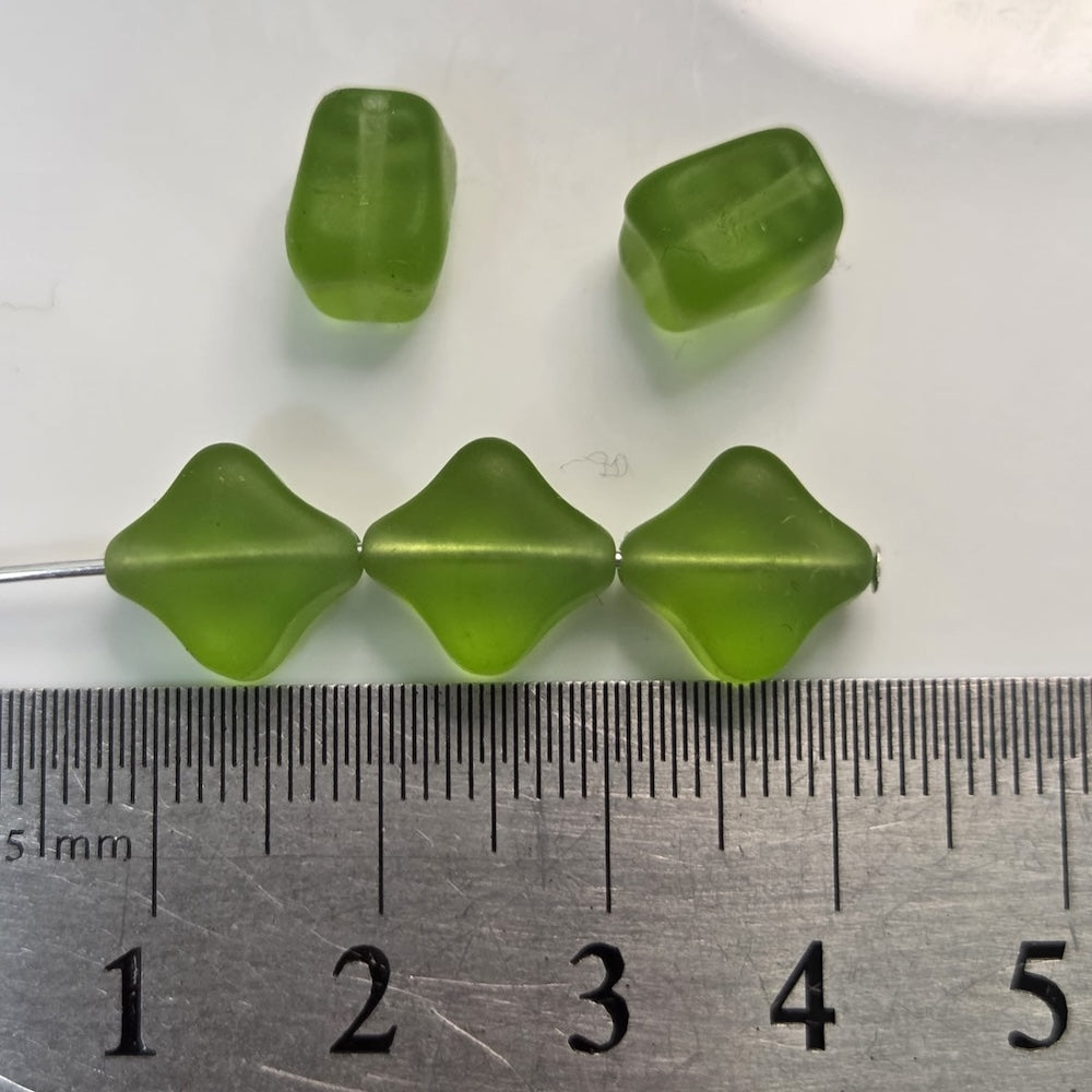 Green beads on a white background with a ruler for scale.