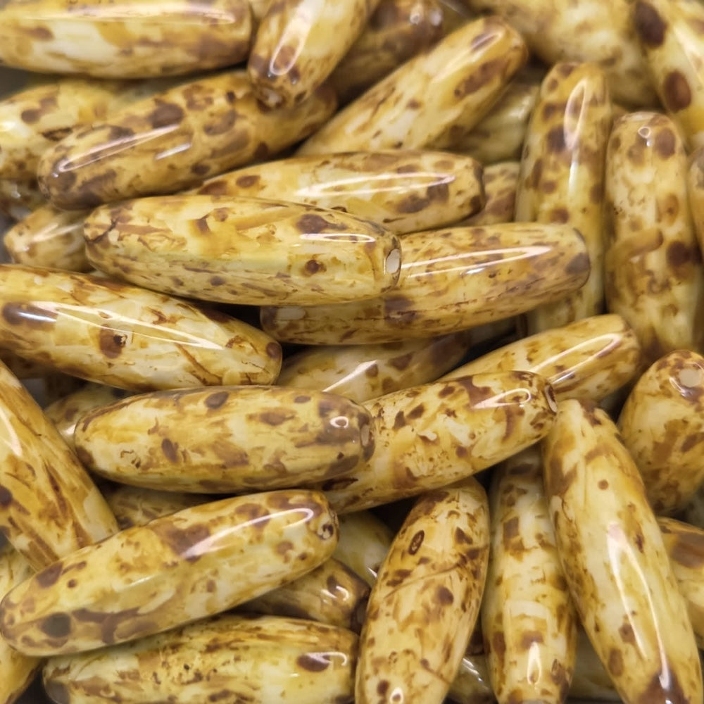 Close-up of a pile of brownish-golden cylindrical beads with dark spots.