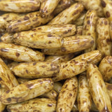 Close-up of a pile of brownish-golden cylindrical beads with dark spots.