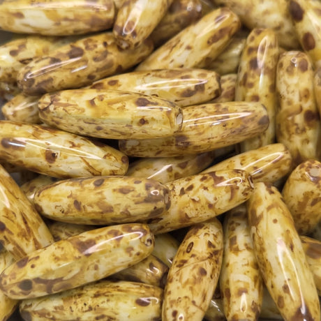 Close-up of a pile of brownish-golden cylindrical beads with dark spots.