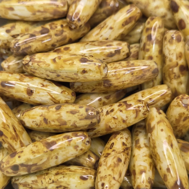 Close-up of a pile of brownish-golden cylindrical beads with dark spots.
