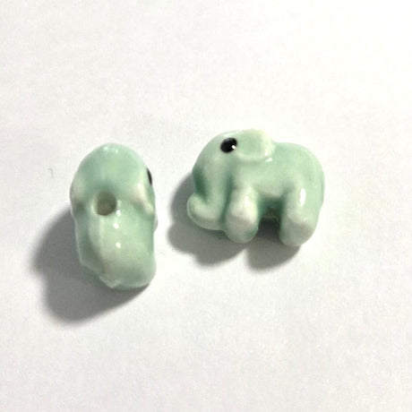 two light green elephant beads made from porcelain ceramic on a white surface