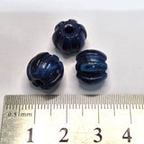 Three blue plastic beads with a ruler for scale on a white background