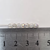 Clear beads on a needle with a ruler for scale on a white background