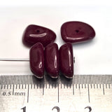 dark red beads on a white background with a ruler for scale